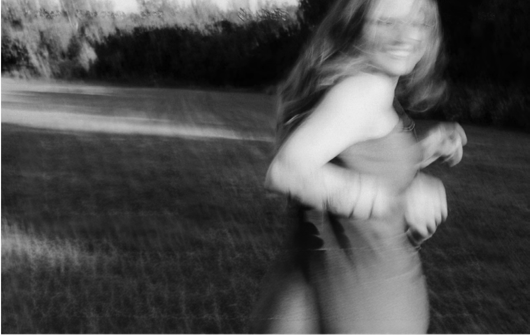 A black-and-white frame of a woman in a summer field.